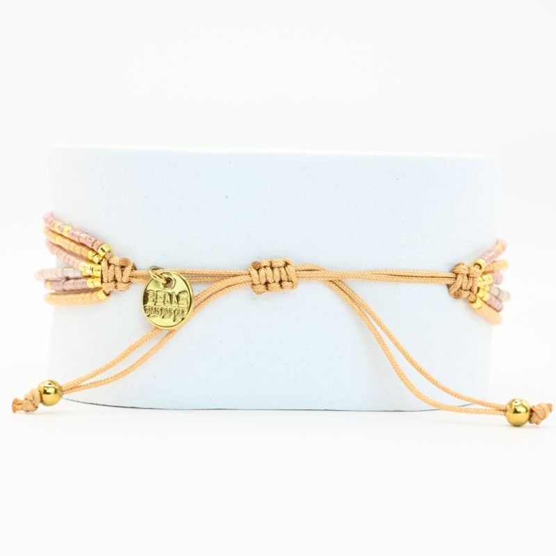 ce bracelet fin à 6 rangs associe des perles dorées et nude pour un look élégant et raffiné. Un ornement traverse les six rangs, créant un effet unique et structuré. . Bijou seul, Crédit GEMITY