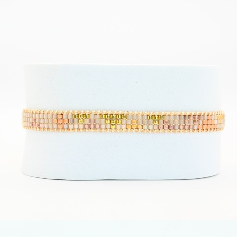 cette mini manchette élégante se compose de 3 rangs de perles nude, dorées et blanches, créant un design délicat et raffiné. . Bijou seul, Crédit GEMITY