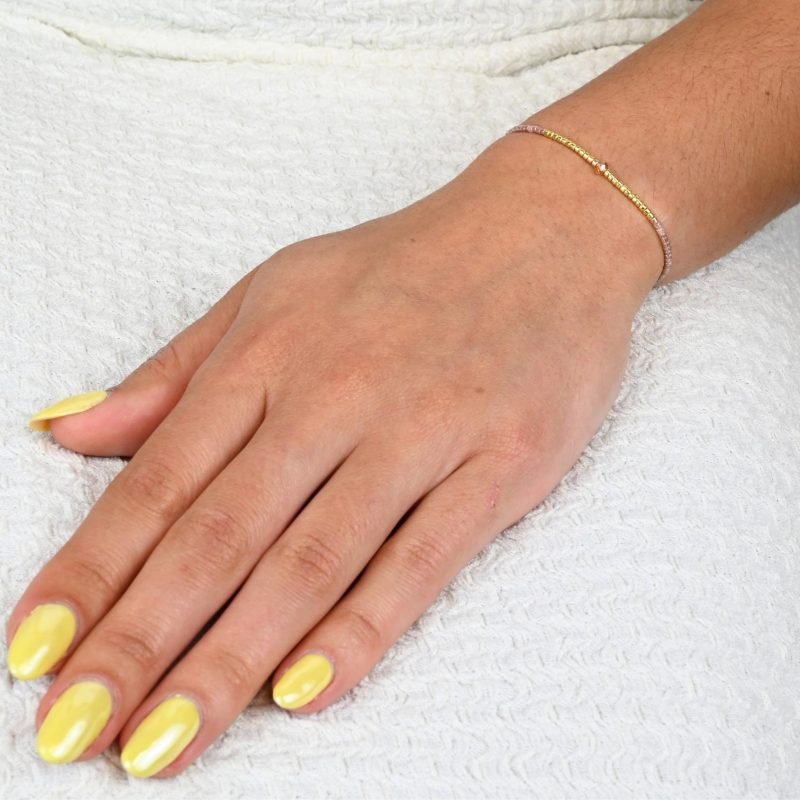 ce bracelet fin à cordon ajustable. Composé de perles nude délicates et de perles dorées au centre, ce bijou 1 rang se marie facilement avec toutes vos tenues. . Bijou porté, Crédit GEMITY.