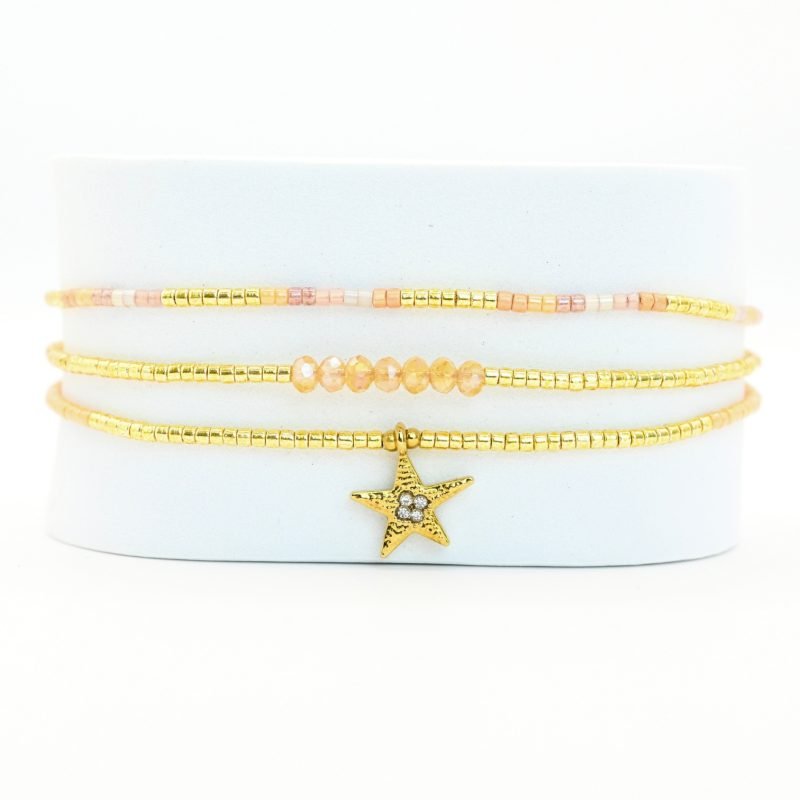 ce bracelet raffiné à 3 rangs combine des perles dorées et nude pour un look élégant et féminin. Le premier rang est orné de perles délicates, tandis que le second présente des perles plus grosses, créant un effet visuel dynamique. Le troisième rang se distingue par un charm étoile au centre, ajoutant une touche de magie et de sophistication. . Bijou seul, Crédit GEMITY