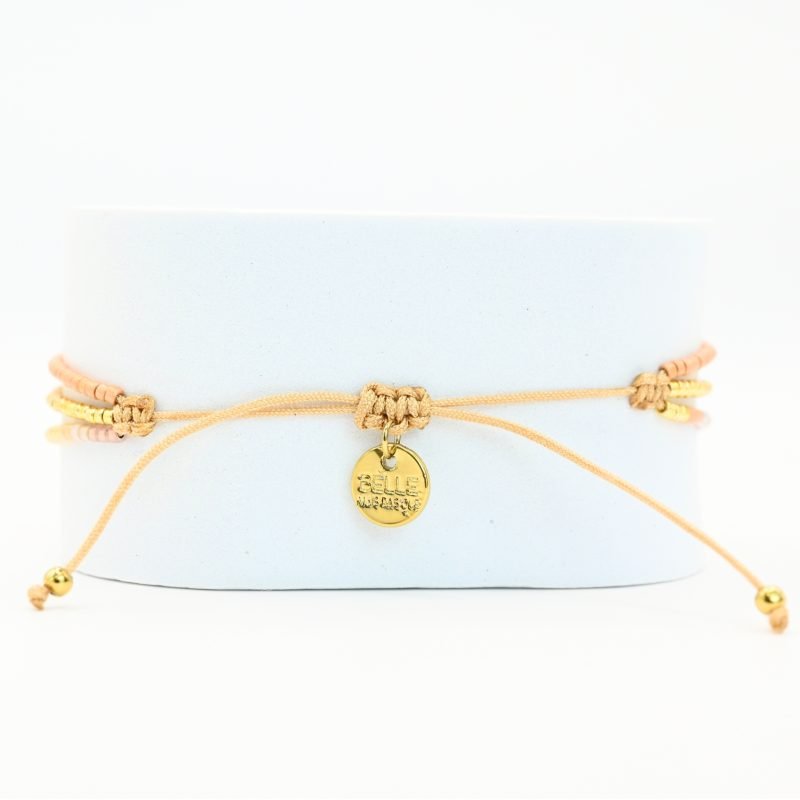 ce bracelet fin à 3 rangs combine des perles dorées, nude et roses, créant une harmonie de couleurs douce et élégante. Le charm rond à strass, placé au centre, ajoute une touche scintillante et raffinée. . Bijou seul, Crédit GEMITY