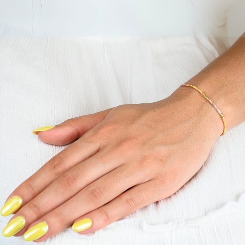 " ce bracelet délicat allie finesse et élégance avec son cordon ajustable et ses perles dorées et rose poudré. . Bijou porté, Crédit GEMITY."