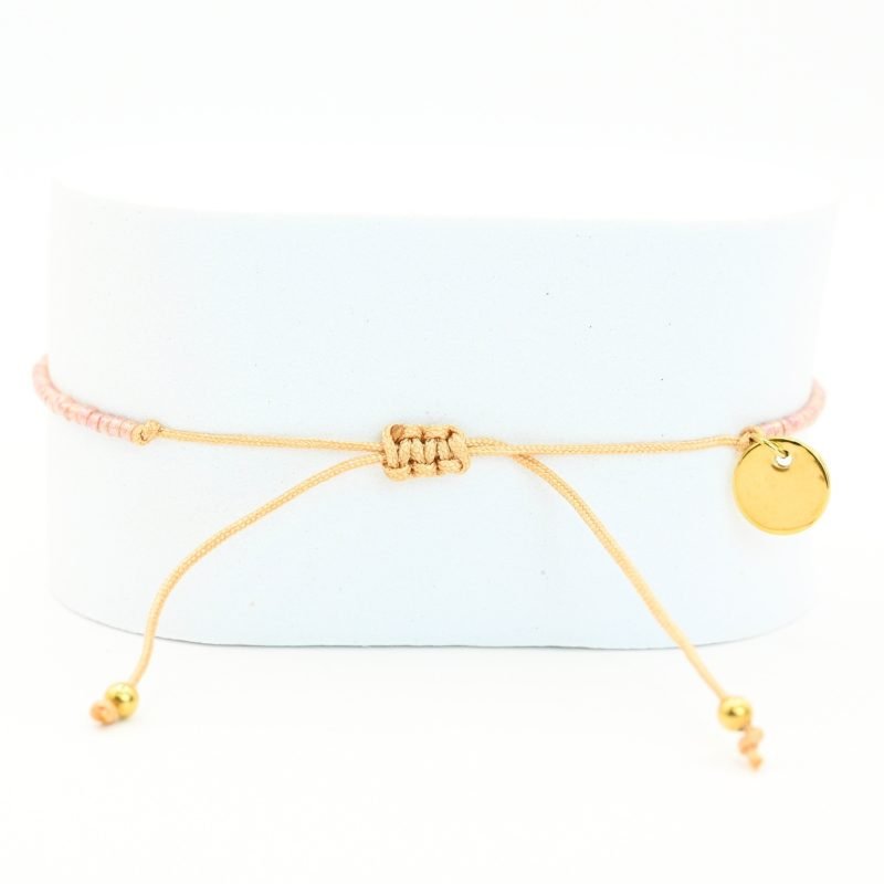 " ce bracelet délicat allie finesse et élégance avec son cordon ajustable et ses perles dorées et rose poudré. . Bijou seul, Crédit GEMITY"
