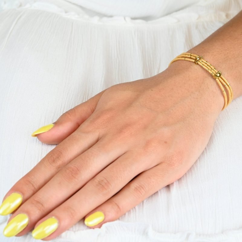 ce bracelet fin à 3 rangs est principalement composé de perles nude, avec quelques touches subtiles de perles dorées, créant un look délicat et élégant. Les trois rangs sont réunis par deux ornements en forme de lune, apportant une touche mystique et raffinée. . Bijou porté, Crédit GEMITY.