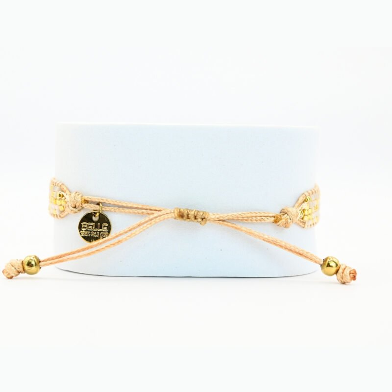 ajoutez une touche de sophistication à votre poignet avec cette petite manchette composée de 5 rangs de perles dorées et blanches. L'ornement doré en son centre apporte une touche de brillance et d'élégance supplémentaire à ce bijou délicat.. Bijou seul, Crédit GEMITY