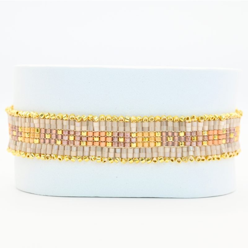 "cette manchette raffinée se compose de 7 rangs de perles, alternant élégance et éclat. Deux rangs extérieurs de perles dorées encadrent des perles nude, tandis que trois rangs centraux dans les tons roses apportent une touche délicate et féminine. . Bijou seul, Crédit GEMITY"