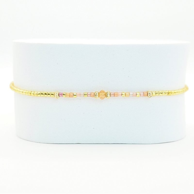 ce bracelet fin et délicat joue sur l’harmonie des couleurs avec son cordon ajustable, ses perles dorées et ses perles dans les tons roses placées en son centre. . Bijou seul, Crédit GEMITY