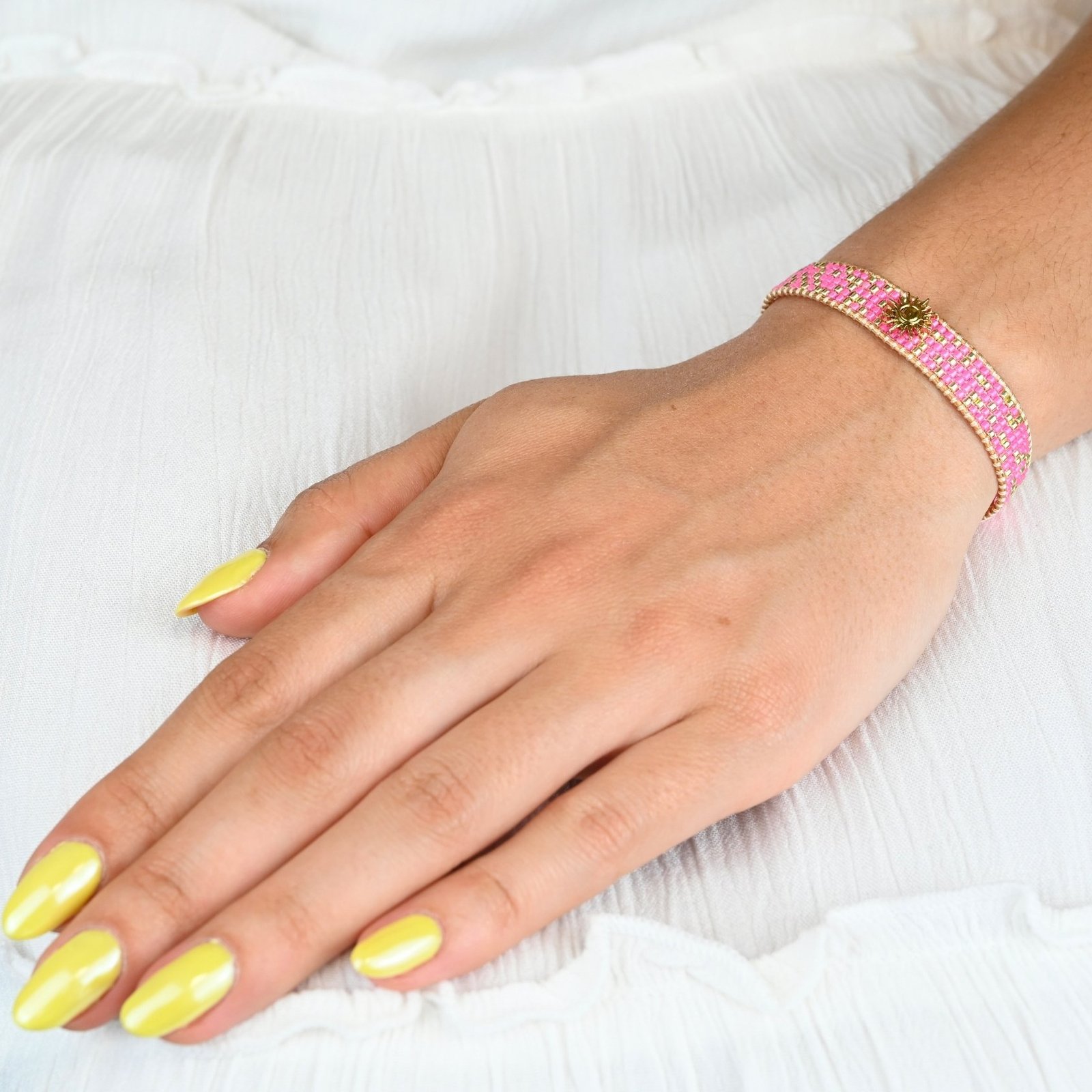 audacieuse et éclatante, cette petite manchette illumine votre poignet avec ses 5 rangs de perles roses fluo. Son ornement central en forme de soleil apporte une touche lumineuse et rayonnante. . Bijou porté, Crédit GEMITY.