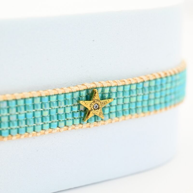 inspirée des nuances apaisantes de l’océan, cette petite manchette se compose de 5 rangs de perles bleues lagon. Son ornement étoile avec un zircon disposé au centre du bracelet apporte une touche lumineuse. . Bijou seul, Crédit GEMITY