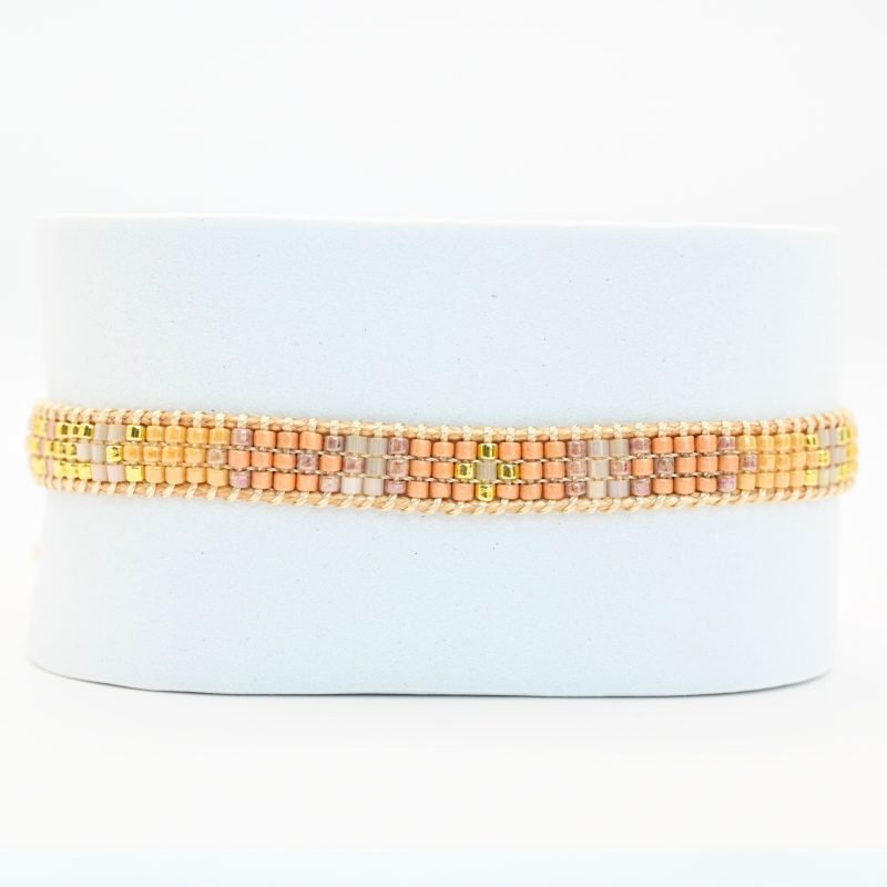 cette mini manchette élégante est composée de 3 rangs de perles nude, dorées et roses poudrées, créant un design doux et féminin. . Bijou seul, Crédit GEMITY