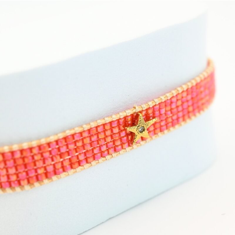 ajoutez une touche de fraîcheur et de lumière à votre poignet avec cette petite manchette élégante. Composée de 5 rangs de perles roses orangées, elle diffuse une couleur douce et chaleureuse. L'ornement étoile en son centre apporte une note délicate et scintillante.. Bijou seul, Crédit GEMITY