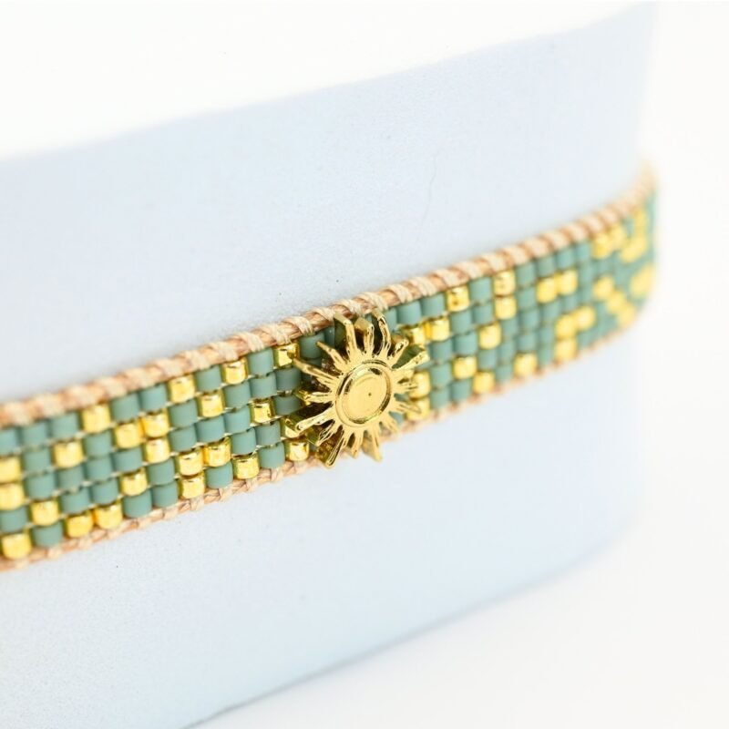 sublimez votre poignet avec cette petite manchette délicate, composée de 5 rangs de perles dorées et vert d'eau qui apportent une touche fraîche et lumineuse. L'ornement soleil au centre ajoute une note rayonnante et éclatante, idéale pour apporter une touche d'élégance à vos tenues.. Bijou seul, Crédit GEMITY