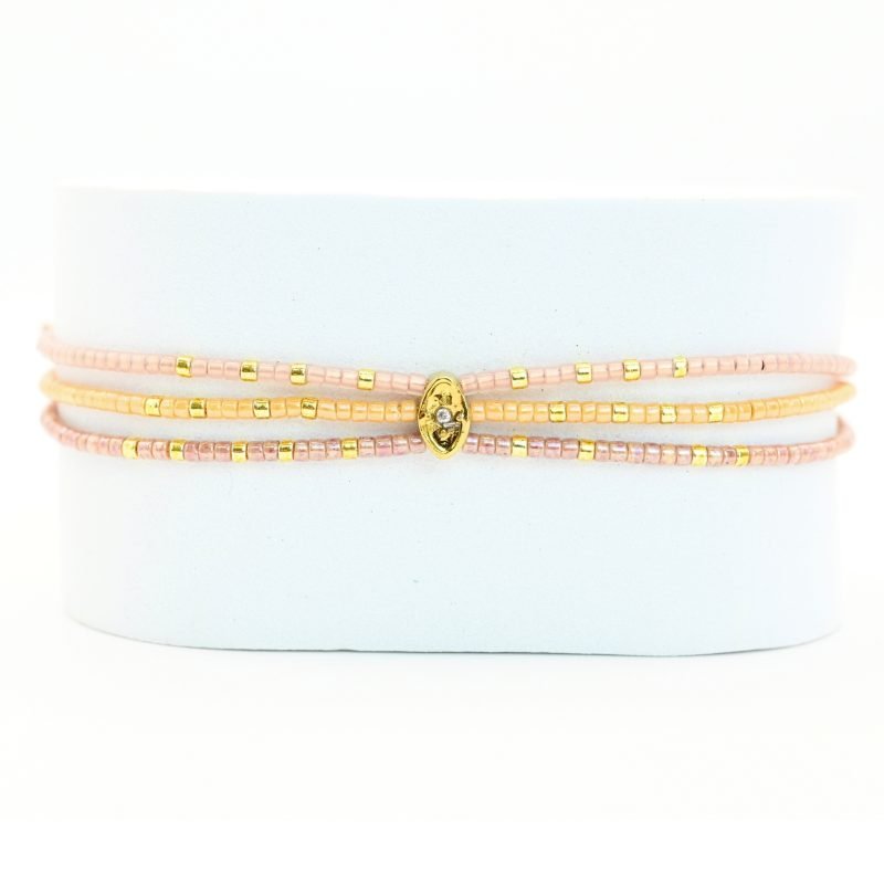 ce bracelet fin à 3 rangs regroupe des perles dorées et nude, créant un effet raffiné et élégant. L'ornement central rassemble les rangs pour un look harmonieux et sophistiqué. . Bijou seul, Crédit GEMITY