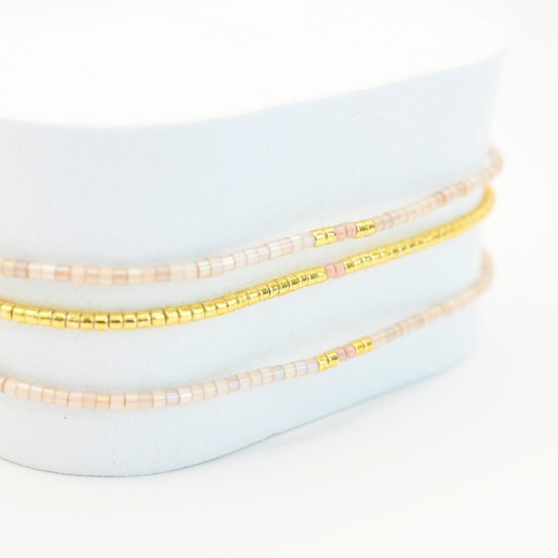 ce bracelet élégant à 3 rangs combine des perles dorées sur le premier rang et des perles blanches sur les deux autres, créant un look raffiné et lumineux. . Bijou seul, Crédit GEMITY