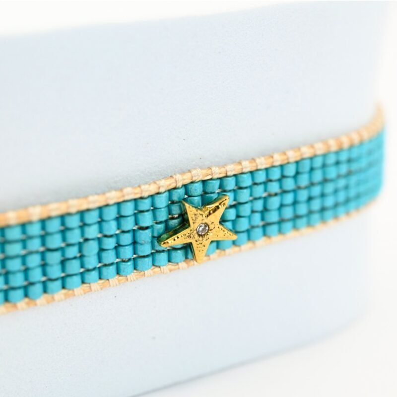 plongez dans l’univers rafraîchissant de cette petite manchette composée de 5 rangs de perles bleues lagon. Le contraste de ses perles vibrantes et l’ornement soleil en son centre créent une harmonie parfaite, évoquant l’éclat du ciel et de la mer. . Bijou seul, Crédit GEMITY