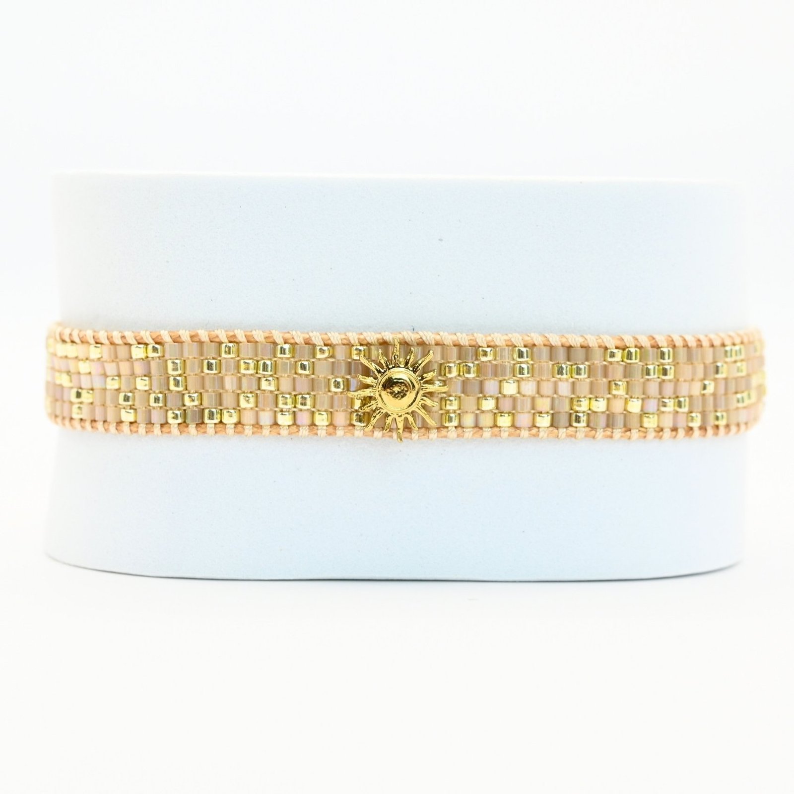 apportez une touche de luminosité à votre poignet avec cette petite manchette élégante. Composée de 5 rangs de perles dorées et nude