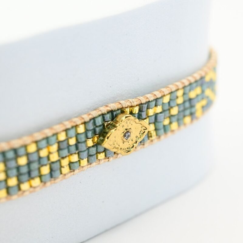 sublimez votre poignet avec cette petite manchette composée de 5 rangs de perles vertes et dorées, qui créent une harmonie parfaite entre fraîcheur et élégance. L'ornement losange central ajoute une touche géométrique et moderne à ce bijou, tout en apportant une note de sophistication.. Bijou seul, Crédit GEMITY