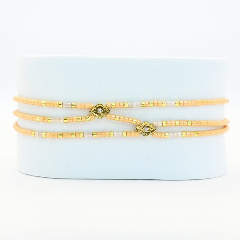 ce bracelet fin à 3 rangs associe des perles dorées et nude, créant un look élégant et discret. Les rangs sont réunis par deux ornements délicats, ajoutant une touche supplémentaire de raffinement et de structure. . Bijou seul, Crédit GEMITY