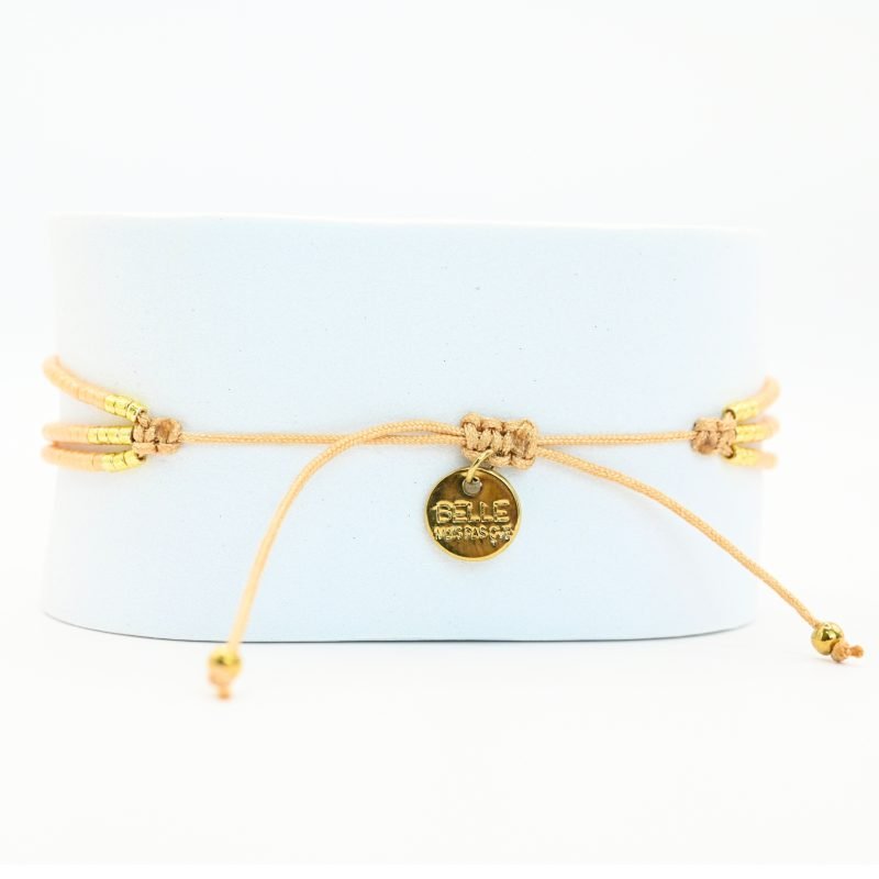 ce bracelet fin à 3 rangs associe des perles dorées et nude, créant un look élégant et discret. Les rangs sont réunis par deux ornements délicats, ajoutant une touche supplémentaire de raffinement et de structure. . Bijou seul, Crédit GEMITY