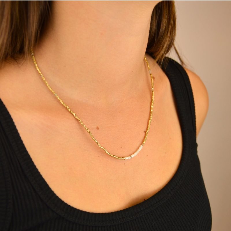 Ce bijou polyvalent se compose de petites perles dorées subtilement mises en valeur par quelques perles en nacre placées en son centre. . Bijou porté, Crédit GEMITY.