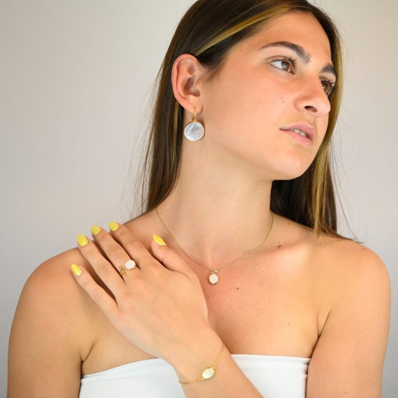 "Collier avec une nacre naturelle montée sur métal doré à l’or fin avec un pendentif en nacre ovale de 1 cm. La longueur de la chaîne est de 40 cm + chaînette de rallonge. . Bijou porté, Crédit GEMITY."
