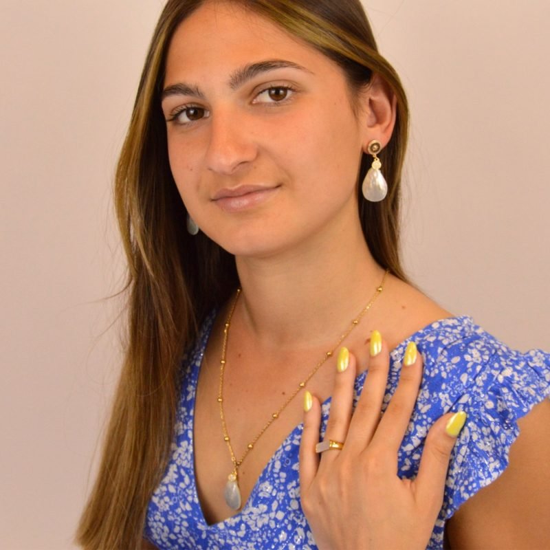 "Boucles d’oreilles en métal, zircons et nacre naturelle. Le pendentif mesure environ 2.5 cm. La nacre Keishi est réputée pour son aspect incomparable. Ce bijou se portera avec délicatesse contre votre peau. . Bijou porté, Crédit GEMITY."