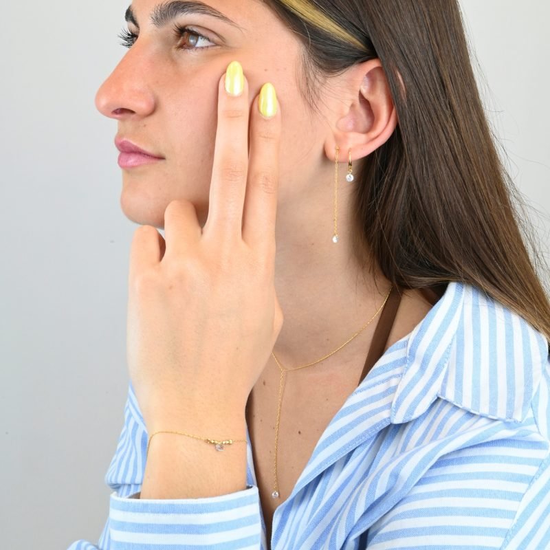 "Bracelet plaqué or (3 microns) avec un zirconium, entouré par des petites perles cylindriques en plaqué or, sur chaîne extra fine . Bijou porté, Crédit GEMITY."