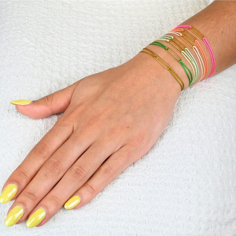 "Bracelet avec un maillon en plaqué or (3 microns) et un cordon coloré. Taille ajustable. . Bijou porté, Crédit GEMITY."