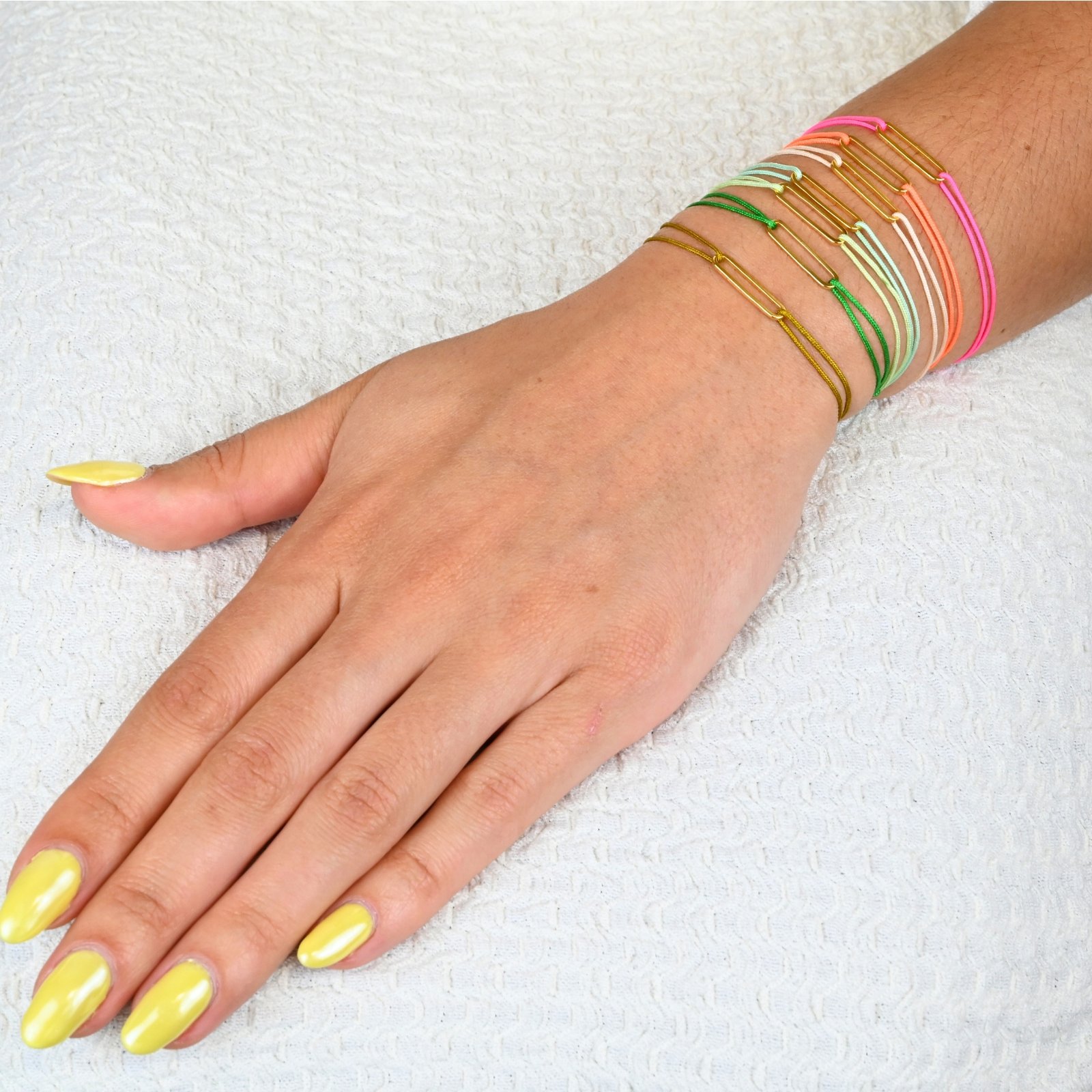 "Bracelet avec un maillon en plaqué or (3 microns) et un cordon coloré. Taille ajustable. . Bijou porté, Crédit GEMITY."