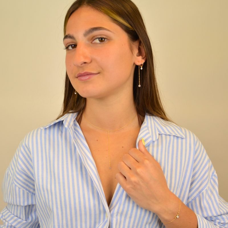 "Bracelet plaqué or (3 microns) avec un zirconium, entouré par des petites perles cylindriques en plaqué or, sur chaîne extra fine . Bijou porté, Crédit GEMITY."