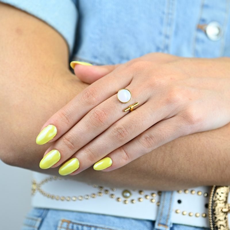 "La couleur blanche de la nacre naturelle s’associera avec tout votre dressing. Une nacre naturelle’ qui a été récupérée en Asie chez le producteur lors de nombreux voyages. Bague nacre RÉGLABLE Composition : métal doré à l'or fin 24 cts . Bijou porté, Crédit GEMITY."