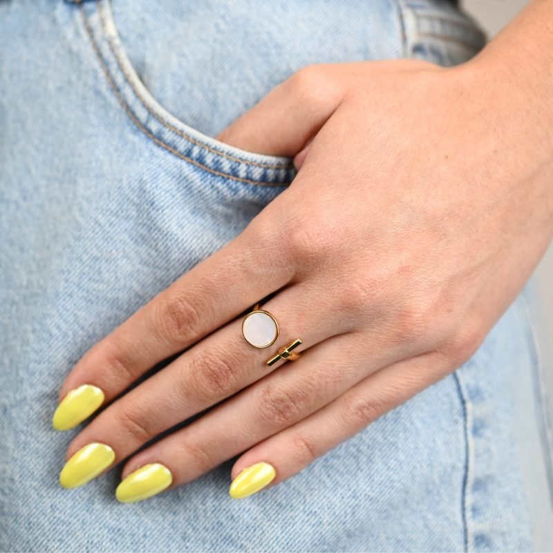 "La couleur blanche de la nacre naturelle s’associera avec tout votre dressing. Une nacre naturelle’ qui a été récupérée en Asie chez le producteur lors de nombreux voyages. Bague nacre RÉGLABLE Composition : métal doré à l'or fin 24 cts . Bijou porté, Crédit GEMITY."