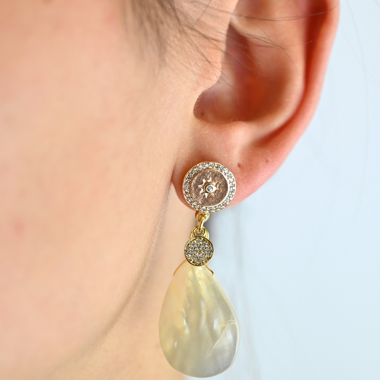 "Boucles d’oreilles en métal, zircons et nacre naturelle. Le pendentif mesure environ 2.5 cm. La nacre Keishi est réputée pour son aspect incomparable. Ce bijou se portera avec délicatesse contre votre peau. . Bijou porté, Crédit GEMITY."