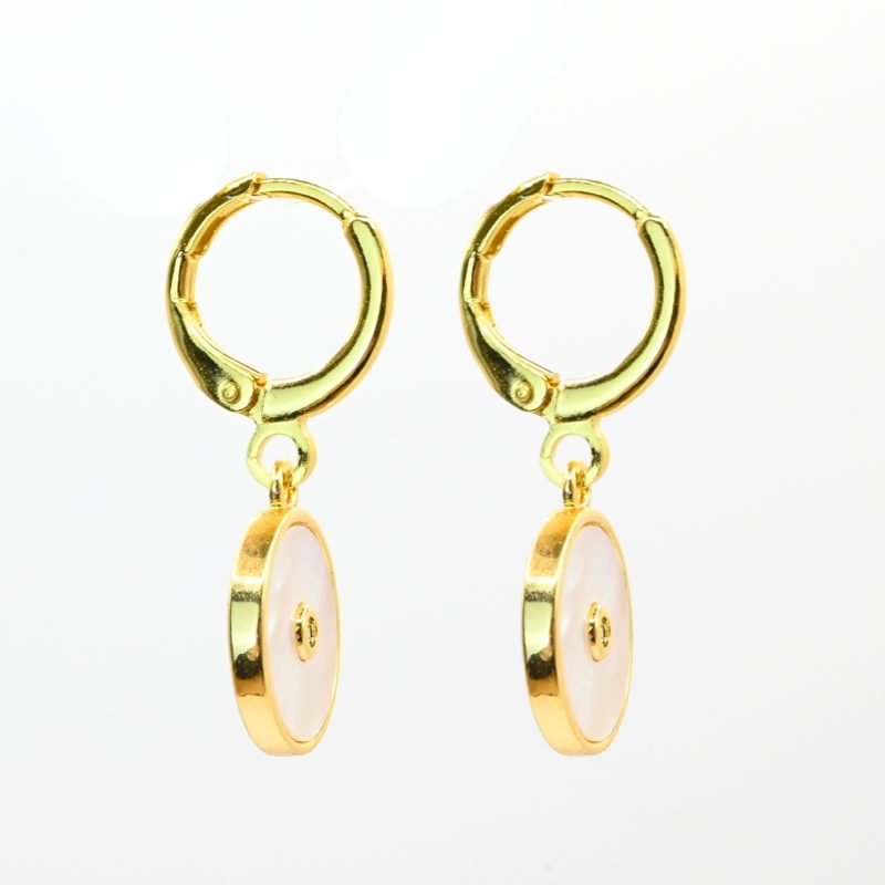 Boucles d'oreilles en métal et cabochon en nacre naturelle de 1 cm. Une nacre naturelle qui se portera avec délicatesse contre votre peau. Elle est composée d’un petit pendentif avec en son centre un zirconium couleur cristal. . Bijou seul, Crédit GEMITY