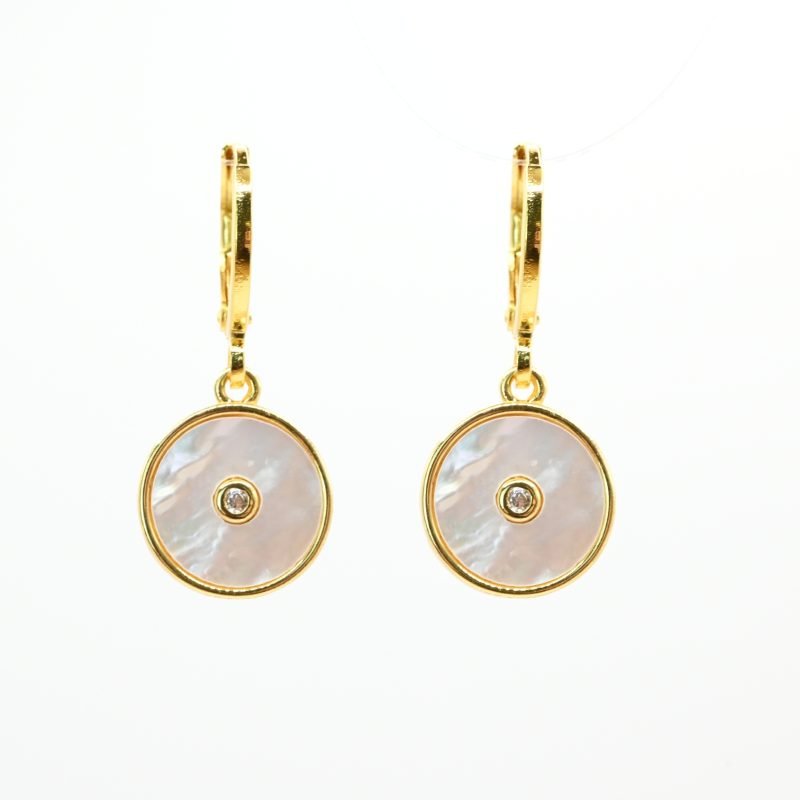 Boucles d'oreilles en métal et cabochon en nacre naturelle de 1 cm. Une nacre naturelle qui se portera avec délicatesse contre votre peau. Elle est composée d’un petit pendentif avec en son centre un zirconium couleur cristal. . Bijou seul, Crédit GEMITY