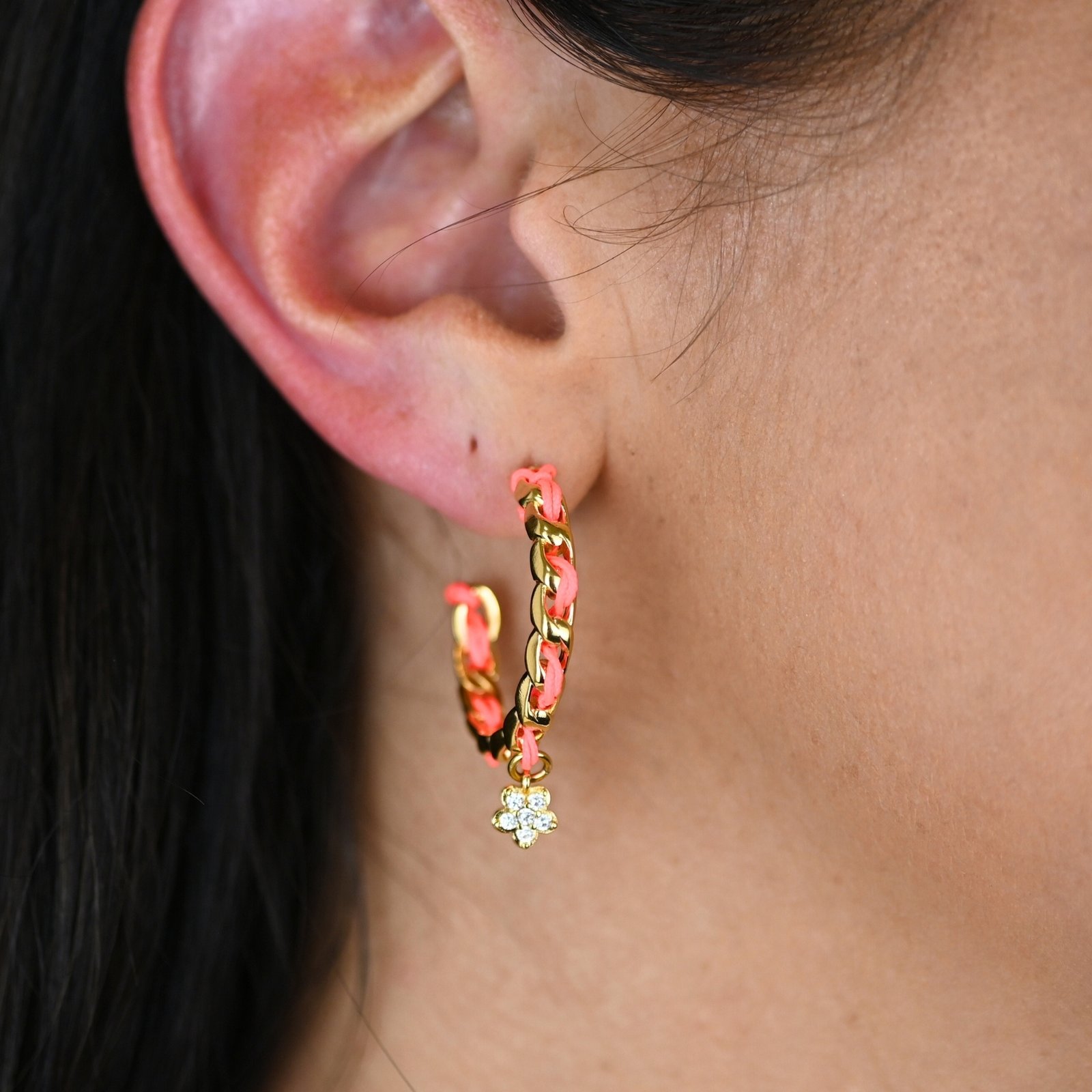 "Les boucles d'oreilles Monsens, inspirées de la collection Couture, où l'on retrouve un célèbre charm et une couleur dominante dans la maille. Taille : 27 mm de diamètre Composition : plaqué or et fil de coton.. Bijou porté, Crédit GEMITY."