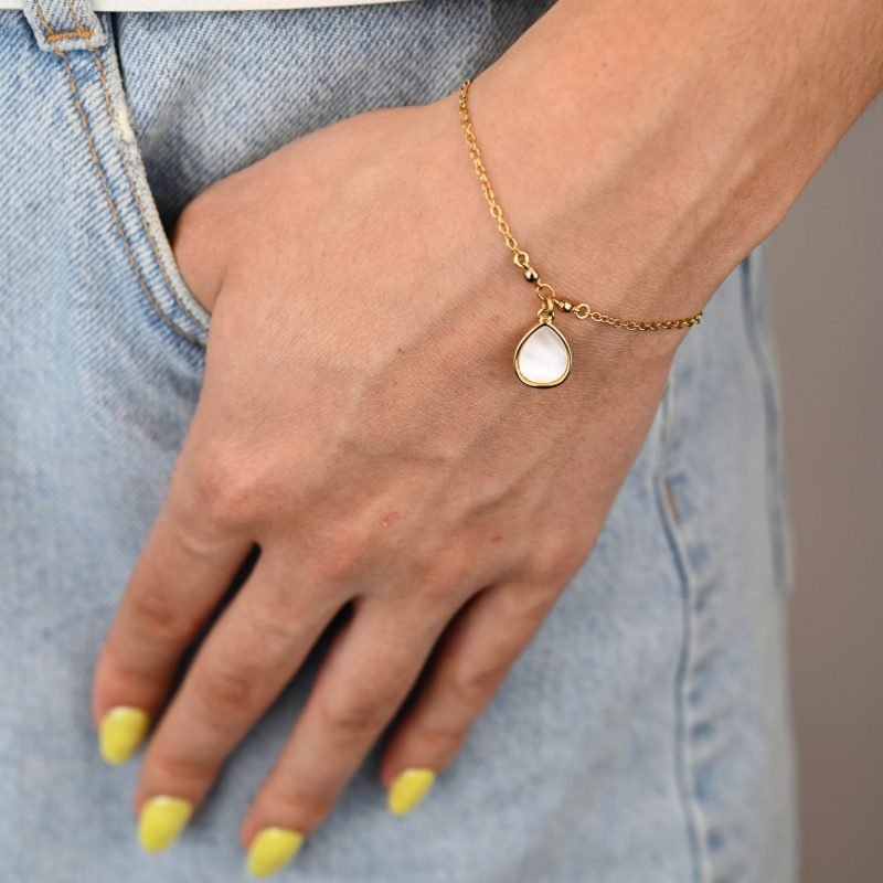 "Si vous appréciez les belles nacres naturelles, vous aimerez la beauté de ce bracelet autour de votre poignet. Ce magnifique bijou est doré à l’or fin 24 carats. Ce bracelet de 15 cm est ajustable avec sa chaîne d’extension. Cette pièce apportera une touche créative à vos tenues dans un style épuré. . Bijou porté, Crédit GEMITY."