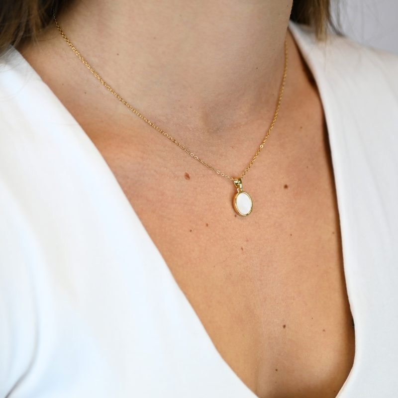 "Collier avec une nacre naturelle montée sur métal doré à l’or fin avec un pendentif en nacre ovale de 1 cm. La longueur de la chaîne est de 40 cm + chaînette de rallonge. . Bijou porté, Crédit GEMITY."