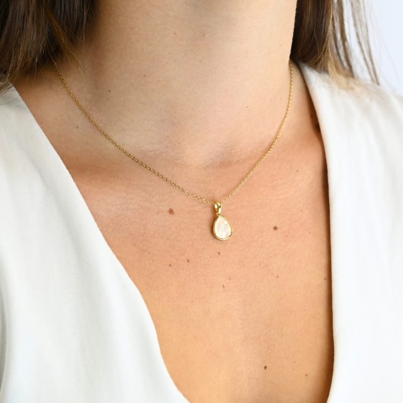 "Collier avec un nacre naturelle montée sur métal doré à l’or fin 24 carats avec un pendentif en forme de goutte d’eau de 1 cm de longueur. La longueur de la chaîne est de 40 cm + chaînette de rallonge. . Bijou porté, Crédit GEMITY."