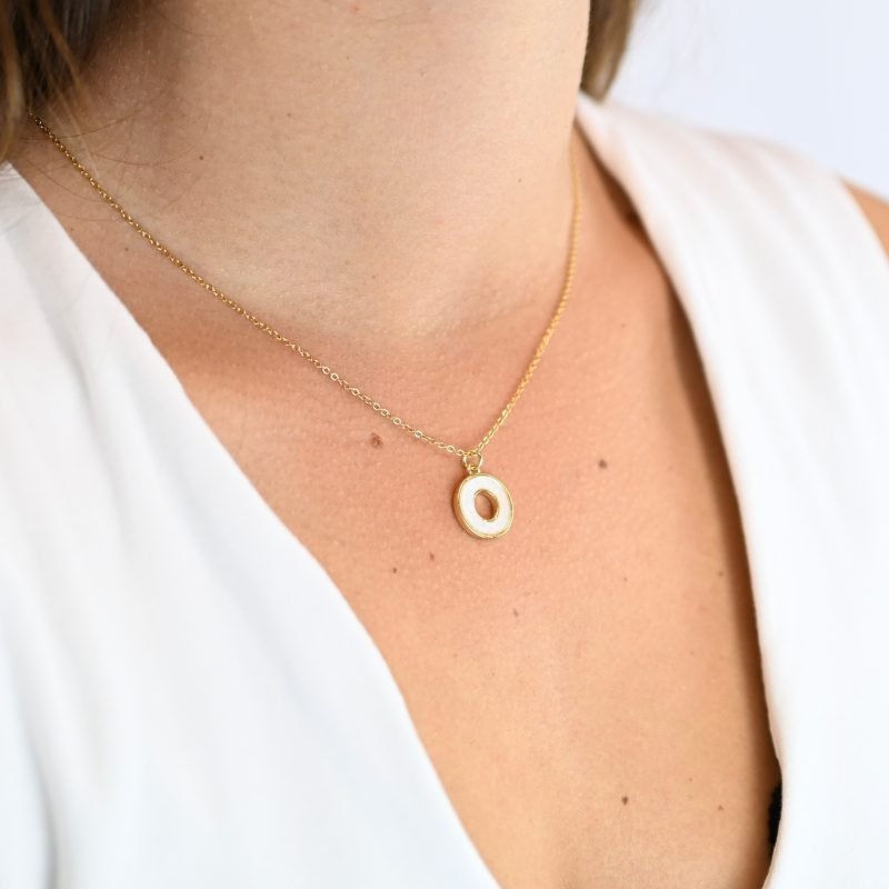 "Collier composé d’un pendentif en nacre naturelle montée sur métal doré à l’or fin 24 carats. La longueur de la chaîne est de 40 cm + chaînette de rallonge. . Bijou porté, Crédit GEMITY."