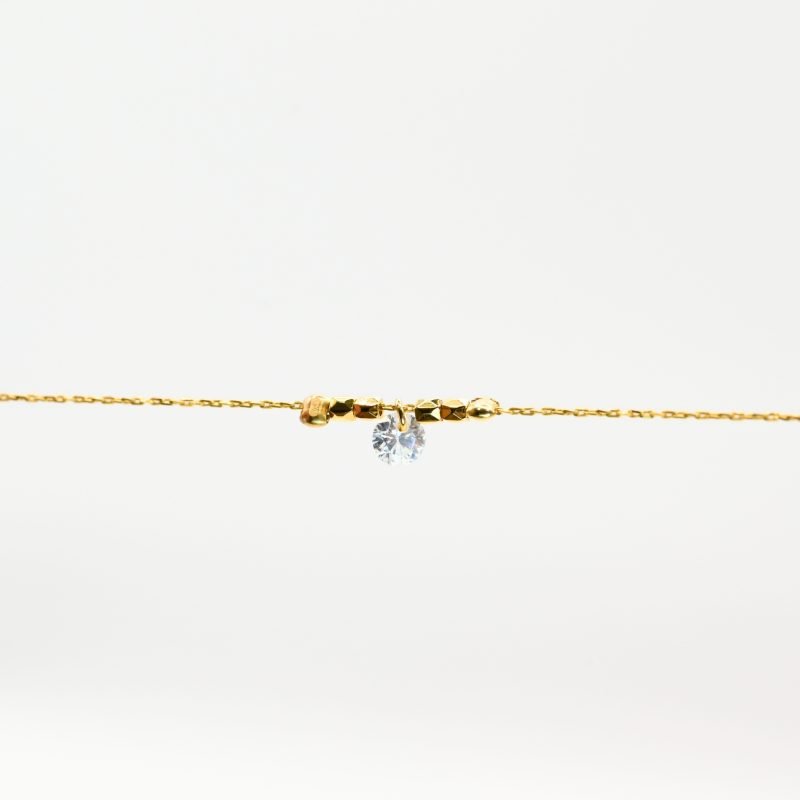 "Bracelet plaqué or (3 microns) avec un zirconium, entouré par des petites perles cylindriques en plaqué or, sur chaîne extra fine . Bijou seul, Crédit GEMITY"