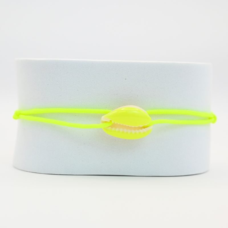 "Véritable cauri émaillé (longueur ≈ 1,5 cm) de la même couleur que le cordon. Lien cordon en coton ajustable, convient pour des poignets de 14 à 19 cm.. Bijou seul, Crédit GEMITY"