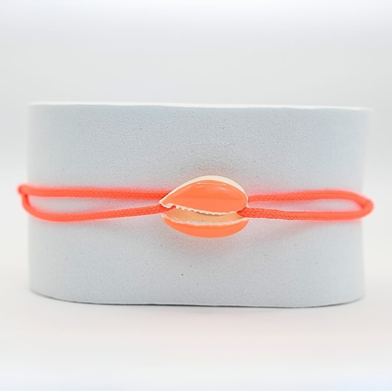 "Véritable cauri émaillé (longueur ≈ 1,5 cm) de la même couleur que le cordon. Lien cordon en coton ajustable, convient pour des poignets de 14 à 19 cm.. Bijou seul, Crédit GEMITY"