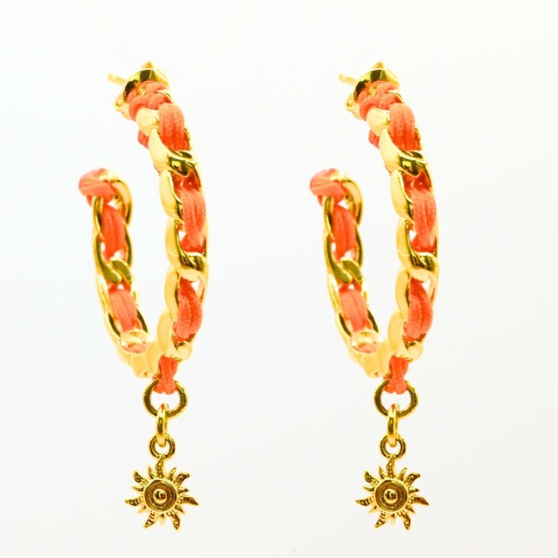 "Les boucles d'oreilles Monsens, inspirées de la collection Couture, où l'on retrouve un célèbre charm et une couleur dominante dans la maille. Taille : 27 mm de diamètre Composition : plaqué or et fil de coton.. Bijou seul, Crédit GEMITY"