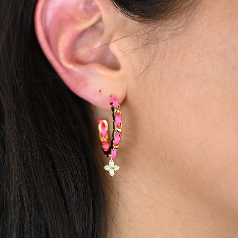 "Les boucles d'oreilles Monsens, inspirées de la collection Couture, où l'on retrouve un célèbre charm et une couleur dominante dans la maille. Taille : 27 mm de diamètre Composition : plaqué or et fil de coton. . Bijou porté, Crédit GEMITY."