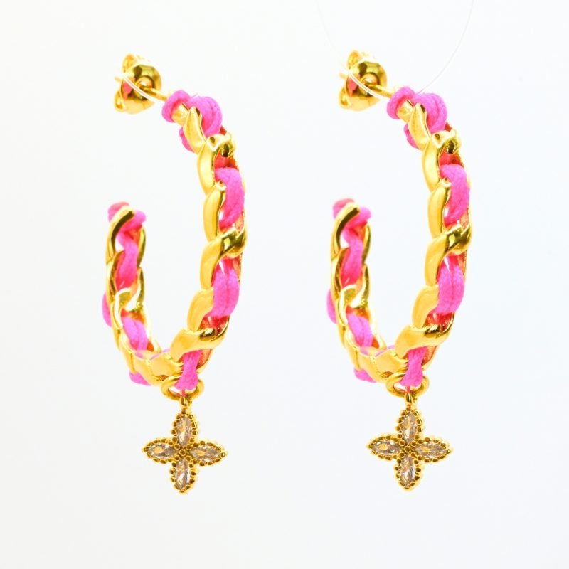 "Les boucles d'oreilles Monsens, inspirées de la collection Couture, où l'on retrouve un célèbre charm et une couleur dominante dans la maille. Taille : 27 mm de diamètre Composition : plaqué or et fil de coton. . Bijou seul, Crédit GEMITY"