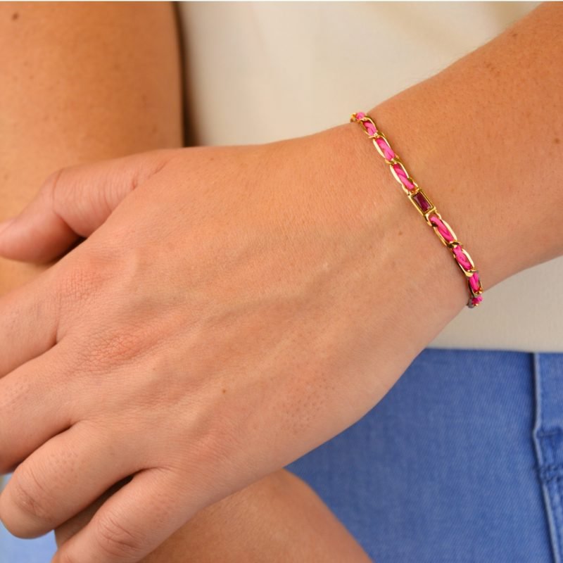 "Bracelet avec un cordon doré et un gemme transparent en son centre. Composition : 100% plaqué or. Contient 1 strass coloré transparent. . Bijou porté, Crédit GEMITY."