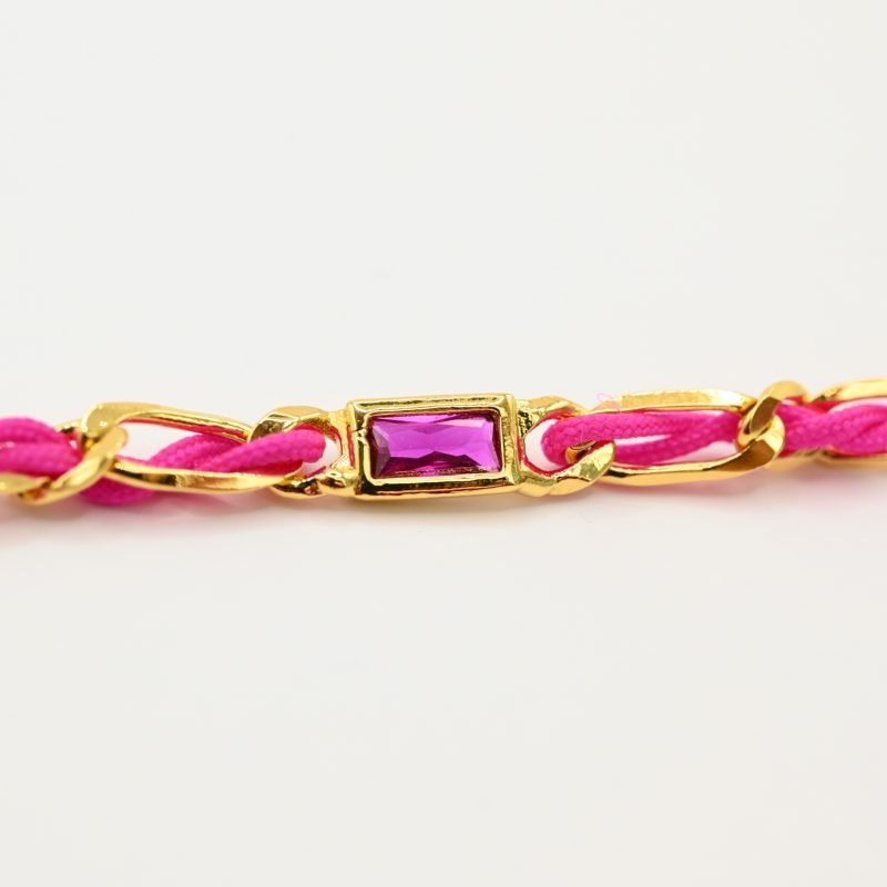 "Bracelet avec un cordon doré et un gemme transparent en son centre. Composition : 100% plaqué or. Contient 1 strass coloré transparent. . Bijou seul, Crédit GEMITY"