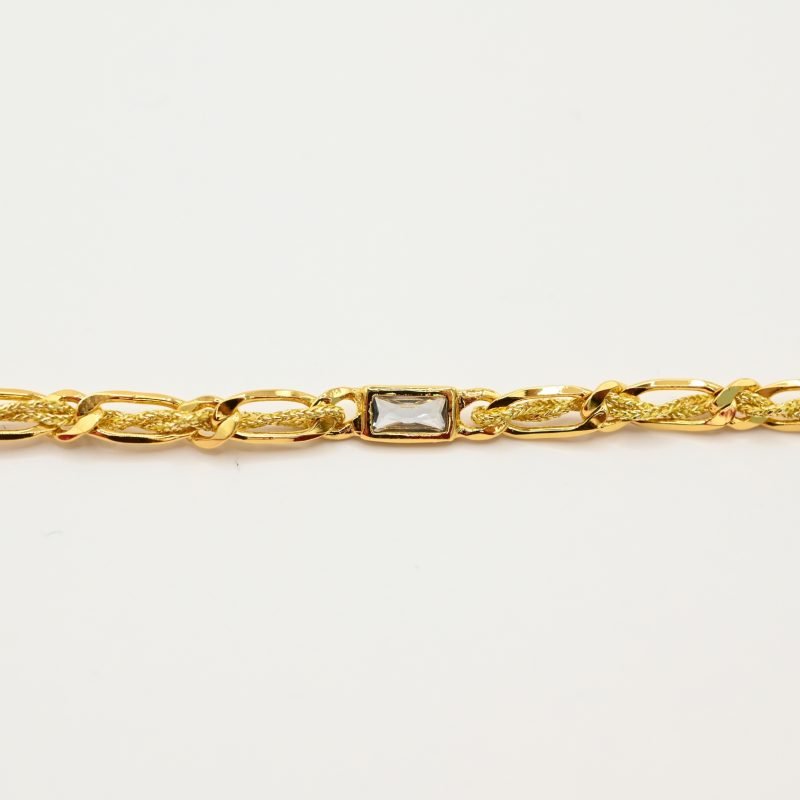 "Bracelet avec un cordon doré et un gemme transparent en son centre. Composition : 100% plaqué or. Contient 1 strass coloré transparent. . Bijou seul, Crédit GEMITY"