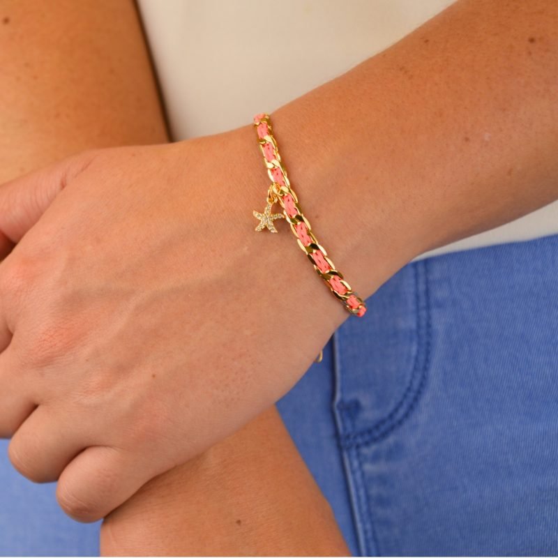 "1 pampille coeur strass Couleur tressage : rose poudré. Fermoir réglable. Matière : plaqué or et incrustation de fils de coton polyester tressés. Utilisation possible sous la douche ! . Bijou porté, Crédit GEMITY."